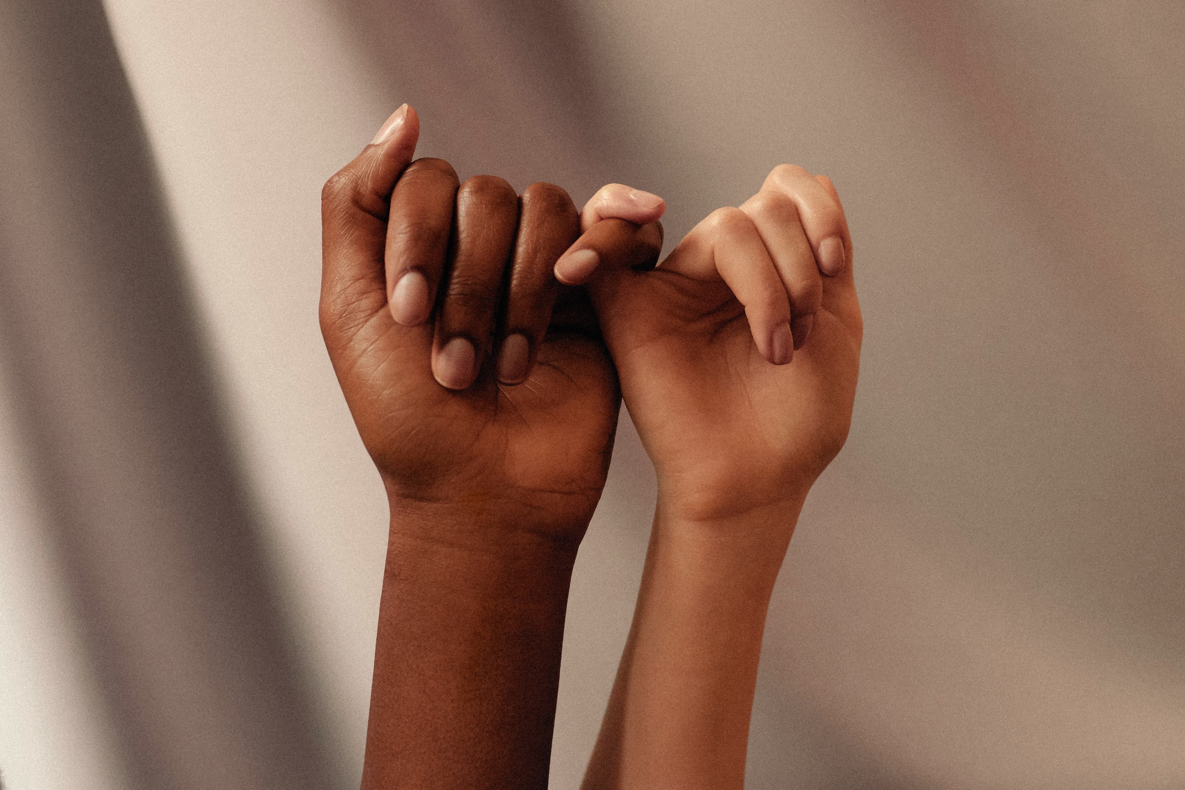 Two women linking hands in support of each other